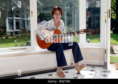 Eileen Rossi moglie di Status Quo rocker Francesco Rossi presso la casa di famiglia in Purley seduti a casa a suonare la chitarra rilassante in una poltrona Foto Stock