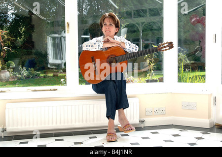 Eileen Rossi moglie di Status Quo rocker Francesco Rossi presso la casa di famiglia in Purley seduti a casa a suonare la chitarra rilassante in una poltrona Foto Stock