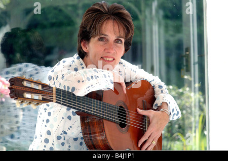 Eileen Rossi moglie di Status Quo rocker Francesco Rossi presso la casa di famiglia in Purley seduti a casa a suonare la chitarra rilassante in una poltrona Foto Stock