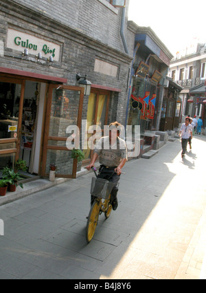 Un uomo corse in bicicletta attraverso la sacca di tabacco street Hutong in Yandai Xiejie a Beijing in Cina Foto Stock