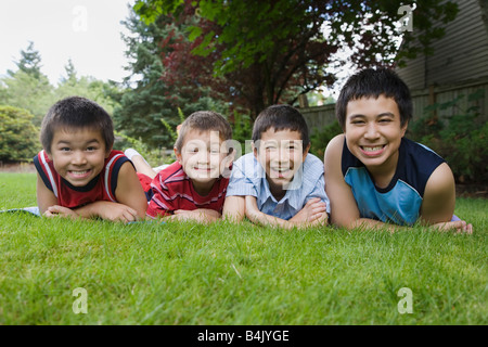 Fratelli asiatici posa in erba Foto Stock