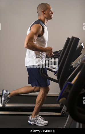 Uomo ispanico in esecuzione sul tapis roulant Foto Stock