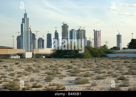 Le gru di Dubai e nuovi edifici in costruzione visto oltre il deserto Foto Stock