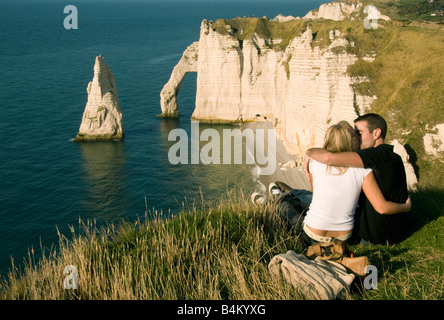 Francia, Normandia, costa, Etretat, giovane trascorrere il tramonto sopra Porte d'Aval Arch e l'Aiguille (ago) Foto Stock