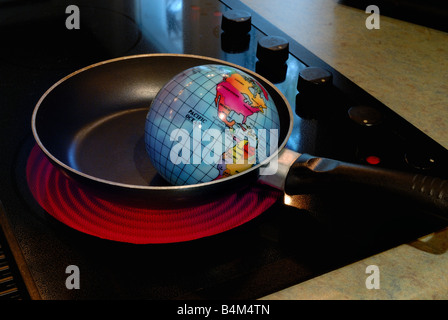 Un globo è mostrato per friggere in una padella su una stufa calda bruciatore che rappresenta il concetto di riscaldamento globale Foto Stock