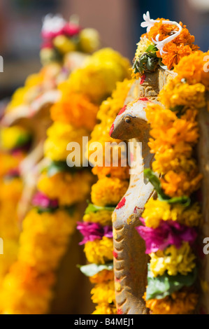 Naga. Cobra indiano divinità Idoli di pietra coperto di ghirlande di fiori per la puja indù cerimonia. Puttaparthi, Andhra Pradesh, India Foto Stock