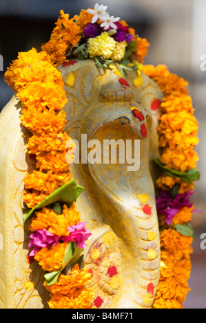 Naga. Cobra indiano divinità Idoli di pietra coperto di ghirlande di fiori per la puja indù cerimonia. Puttaparthi, Andhra Pradesh, India Foto Stock