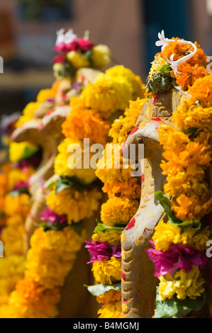 Naga. Cobra indiano divinità Idoli di pietra coperto di ghirlande di fiori per la puja indù cerimonia. Puttaparthi, Andhra Pradesh, India Foto Stock