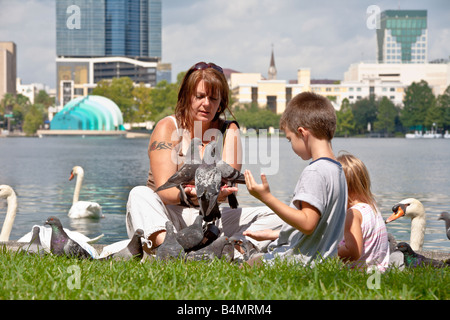 Donna e bambini alimentazione manuale piccioni a Lake Eola Park nel centro cittadino di Orlando in Florida Foto Stock