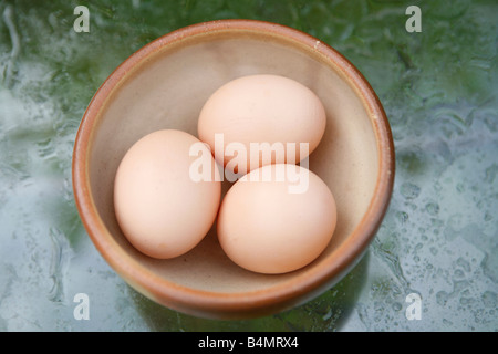 Tre uova in una ciotola su un tavolo di vetro Foto Stock
