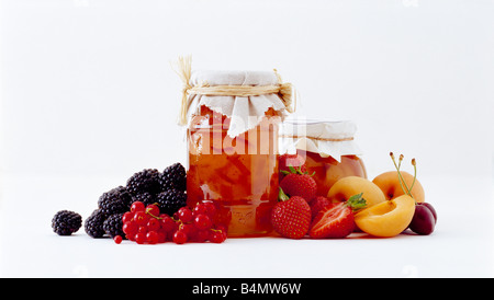 Una selezione di frutta e due 2 pot vasi di marmellata fatta in casa o jelly preservare shot su sfondo bianco Foto Stock