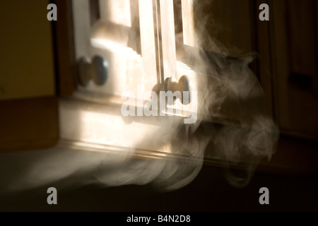 Soffietto di fumo fuori da sotto un armadio Foto Stock