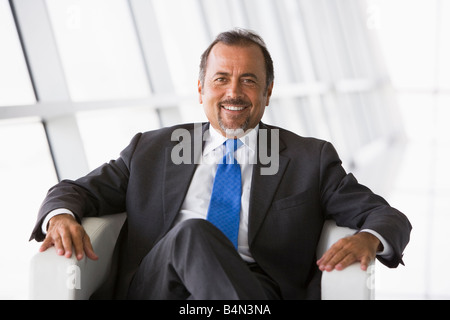 Imprenditore seduta indoor sorridente (alta chiave/messa a fuoco selettiva) Foto Stock