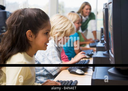 Bambini a terminali di computer con insegnante in background (profondità di campo/high key) Foto Stock