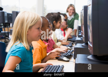 Bambini a terminali di computer con insegnante in background (profondità di campo/high key) Foto Stock