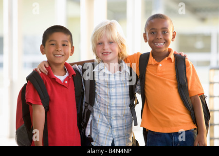 Tre studenti al di fuori della scuola in piedi insieme sorridente (messa a fuoco selettiva) Foto Stock