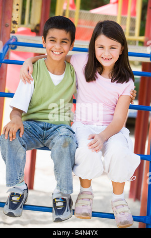 Due giovani bambini seduti sulla struttura di gioco sorridente (messa a fuoco selettiva) Foto Stock