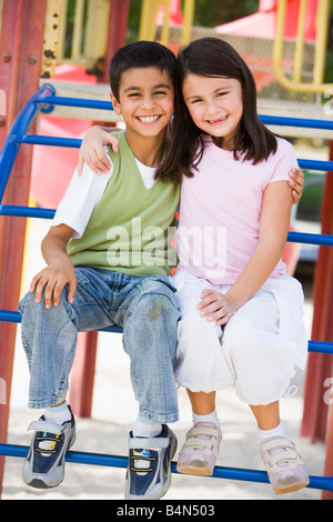 Due giovani bambini seduti sulla struttura di gioco sorridente (messa a fuoco selettiva) Foto Stock