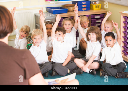 Gli studenti in classe seduti sul pavimento di volontariato per insegnante (messa a fuoco selettiva) Foto Stock