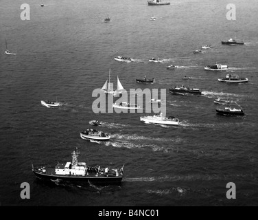 Barca a vela aprile 1969 la fine del 1968 1969 Golden Globe per il giro del mondo in gara mostrando il Suhaili imbarcazione appartenente a Robin Knox Johnston essendo scortato oltre la linea da una armata di barche a Falmouth Foto Stock