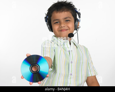 Ragazzo asiatico di origine indiana con la sua cuffia sul e tenendo un compact disc Foto Stock