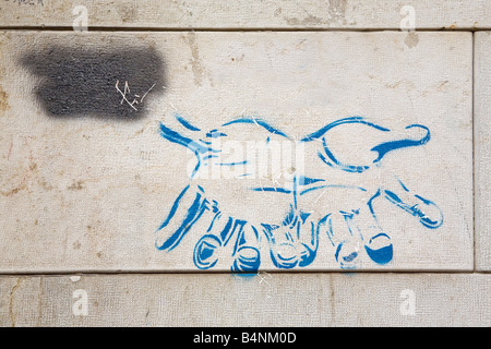 Arte di strada mani dipinta su un muro al di sopra di un percorso Foto Stock