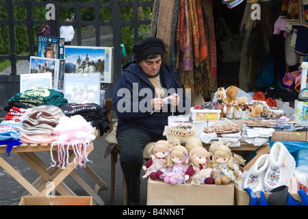 Transilvania Romania UE settembre una donna rumena stallholder crochetting mentre in attesa di clienti per il suo negozio di souvenir Foto Stock