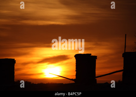 Silhouette di camini retroilluminati da tramonto. Foto Stock