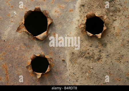 Fori di proiettile con centro nero in ferro piatto arrugginito Foto Stock