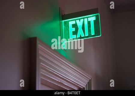 Un incandescente segno verde indica un edificio uscita di emergenza Foto Stock