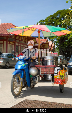 Mobile di ice-cream vendor, vendita di gelato e indossando maschera per fornire protezione contro inquinanti delle emissioni del veicolo, Hua Hin, Thailandia. Foto Stock