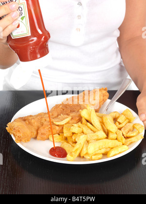 Giovane donna mettendo il ketchup sul pesce e patatine modello rilasciato Foto Stock