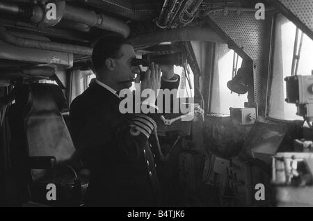 Esercitazione NATO 1965 HMS Ark Royal Portaerei Marzo 1965 il capitano guarda attraverso il suo binocolo dal ponte della Ark Royal mentre si tiene il suo tubo Mirrorpix Foto Stock