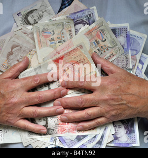 Pila di contanti composta da sterline inglesi banconote e mani che tengono denaro a mans petto & Trattenuta afferrando le dita un'immagine concettuale Inghilterra Foto Stock