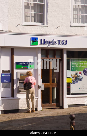 Donna di mezza età prelievo contanti da bancomat al di fuori del Lloyds TSB Bank in Bungay, Suffolk, Regno Unito Foto Stock