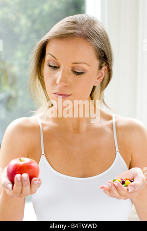 Ragazza rendendo la scelta tra un sano/alimenti dannosi per la salute Foto Stock