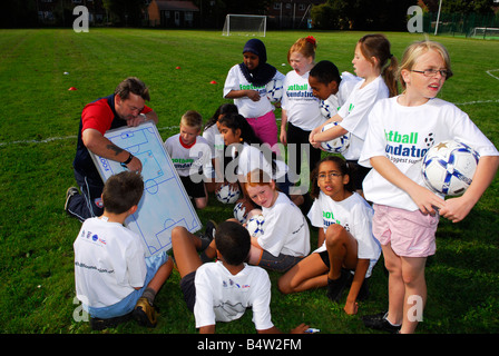 FA coach istruiscono i bambini della scuola elementare nel calcio le competenze e le tattiche, Hounslow, Middlesex, Regno Unito. Foto Stock