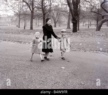 Princess Anne 4 e il Principe Carlo 6 a piedi attraverso il parco verde con la loro governante al loro ritorno a Buckingham Palace dopo la visita della Regina Madre al Clarence House visitatori al Parco erano ignari del Royal i bambini che stavano godendo un po' di libertà sono stati scortati da una distanza da una guardia del corpo reale l'immagine è stata presa da uno specchio fotografo Arthur Sidey che avevano ricevuto una soffiata circa la passeggiata nel parco Arthur non sapendo che il percorso del Royal bambini avrà chiesto a due dei suoi colleghi Dixie Dean e Bob Hope per coprire altre due possibili percorsi attraverso il parco Arthur Foto Stock