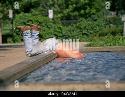 Una persona senza dimora di prendere un bagno e lavare i capelli in una fontana in Victoria Square, Montreal Canada. Foto Stock