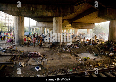 Una folla di persone che vivono in baraccopoli sotto il ponte da Delhi a Bharatpur linea ferroviaria, New Delhi, India Foto Stock
