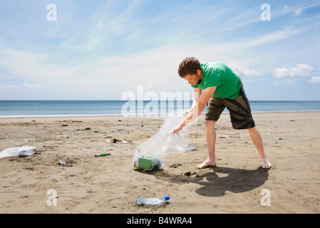Giovane uomo raccogliere rifiuti sulla spiaggia Foto Stock