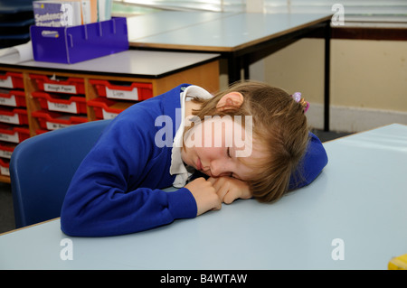 Schoolgirl addormentato sulla sua scrivania allievo dormire in aula scolastica Foto Stock