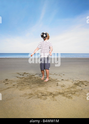 Giovane uomo con il calcio sulla spiaggia Foto Stock