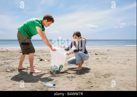 Coppia giovane raccogliere rifiuti sulla spiaggia Foto Stock