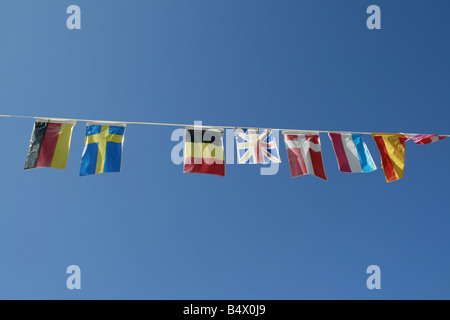 Vecchio sbiadite bandiere internazionali battenti in vento in sun Foto Stock
