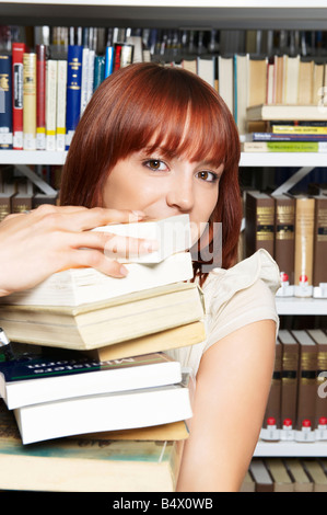 Giovane donna che porta pila di libri Foto Stock