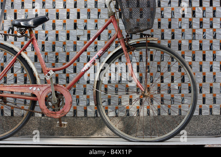 Il vecchio donna bicicletta appoggiata contro una parete piastrellata. Foto Stock