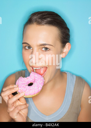 Giovane donna mangiare ciambella Foto Stock