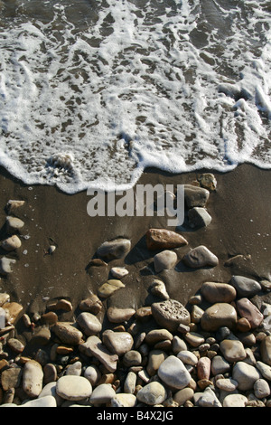 Onde che si infrangono sulle rocce di sabbia sul mare costa Foto Stock