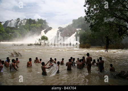 Gli uomini godono di giocare in acqua sotto il Gangachukki rigonfiato e Bharachukki cascate a Sivasudram in Karnataka, India. Foto Stock